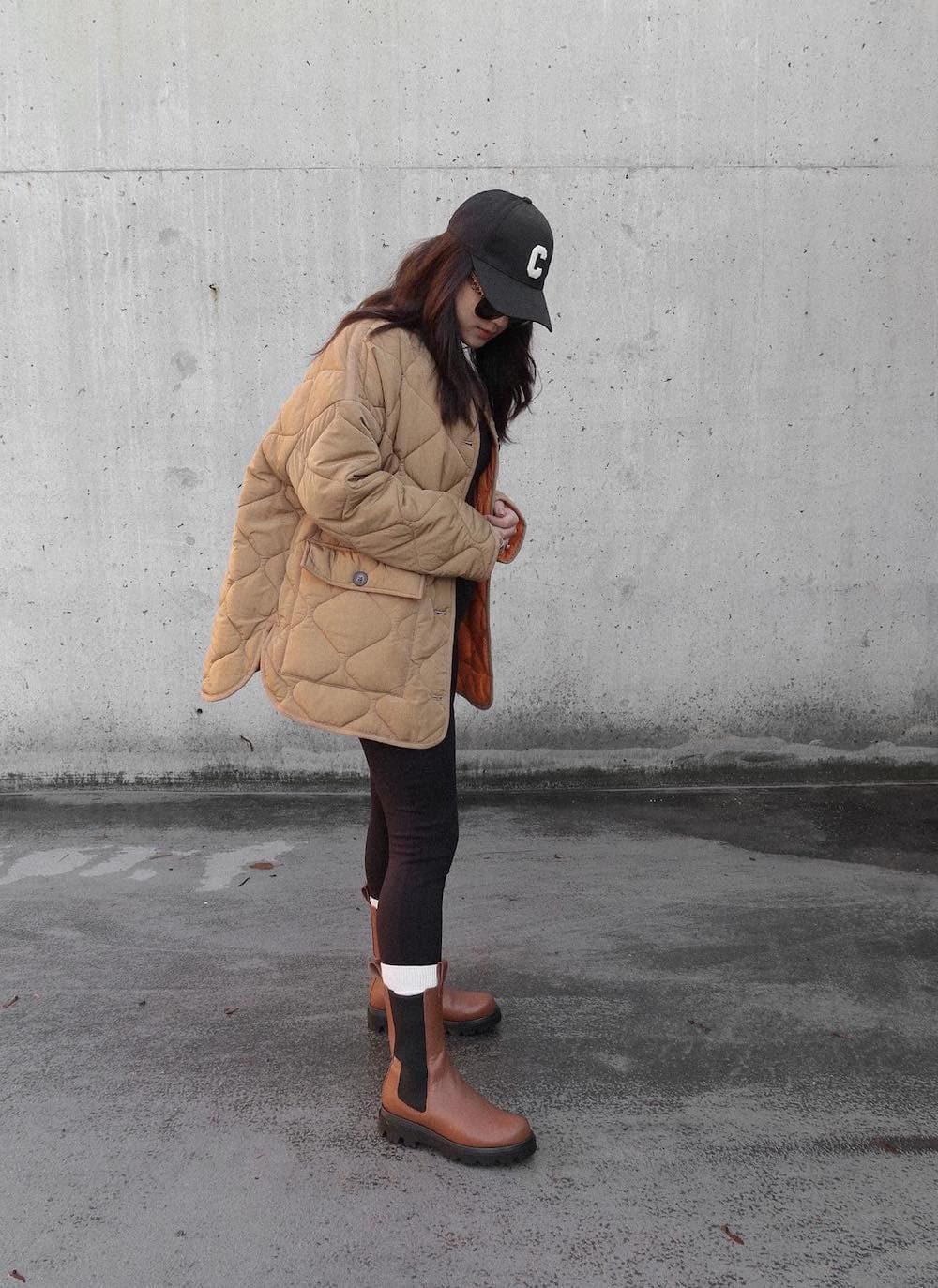 a women wearing a beige quilted jacket, dark brown pants, and brown leather chelsea boots