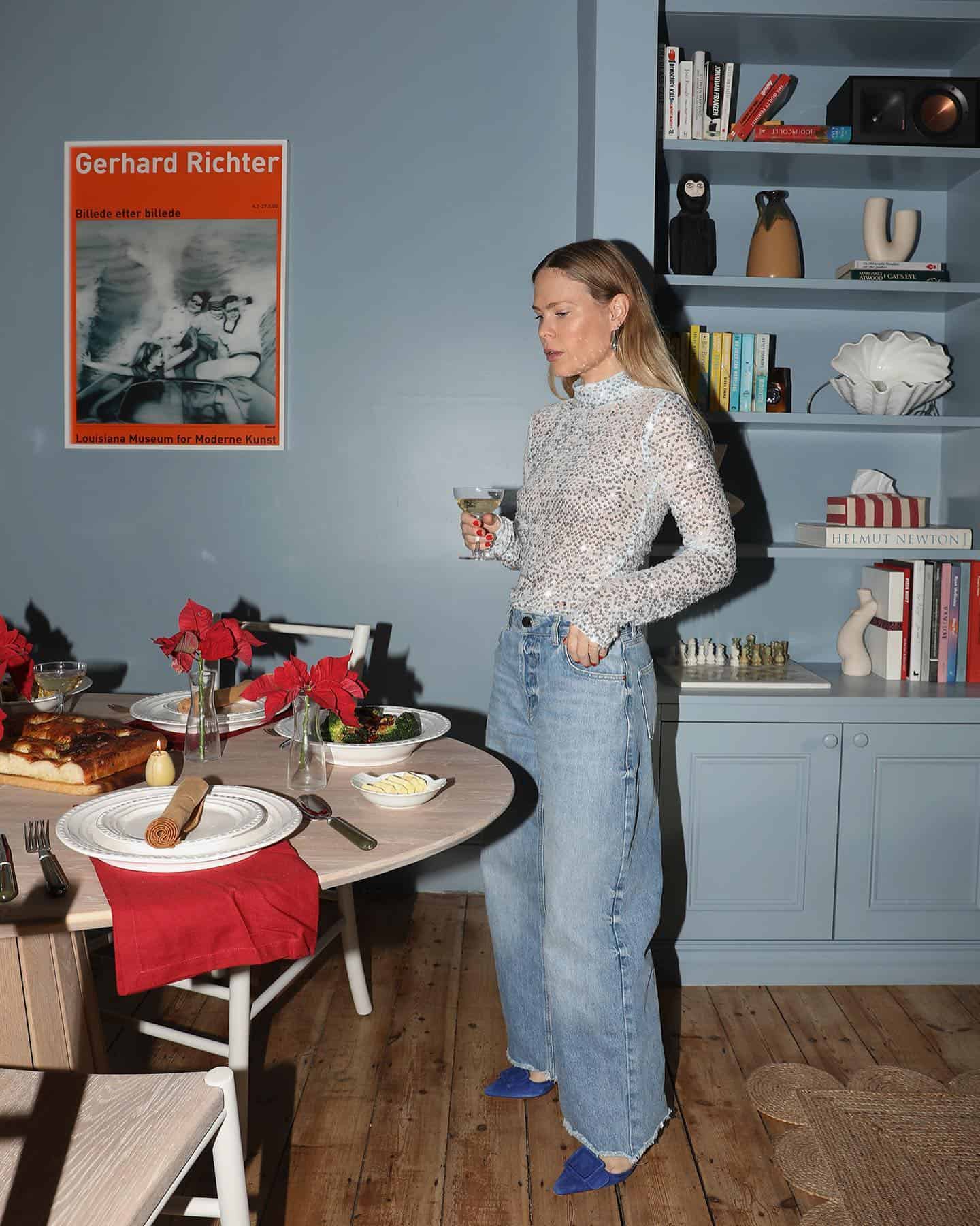 Woman wearing baggy jeans with a sequined top and blue heels.