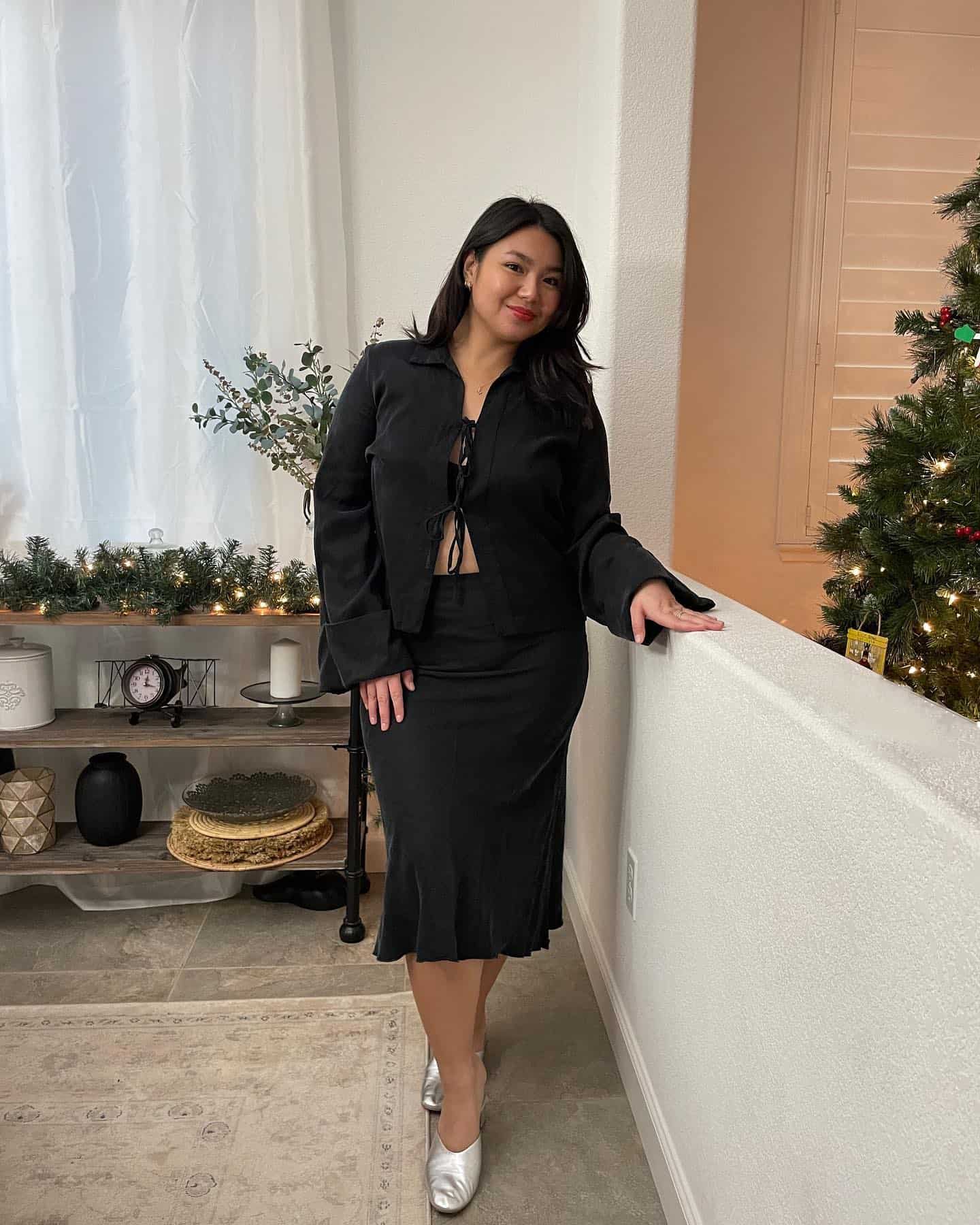 Woman wearing a black slip skirt with a black top and silver shoes.