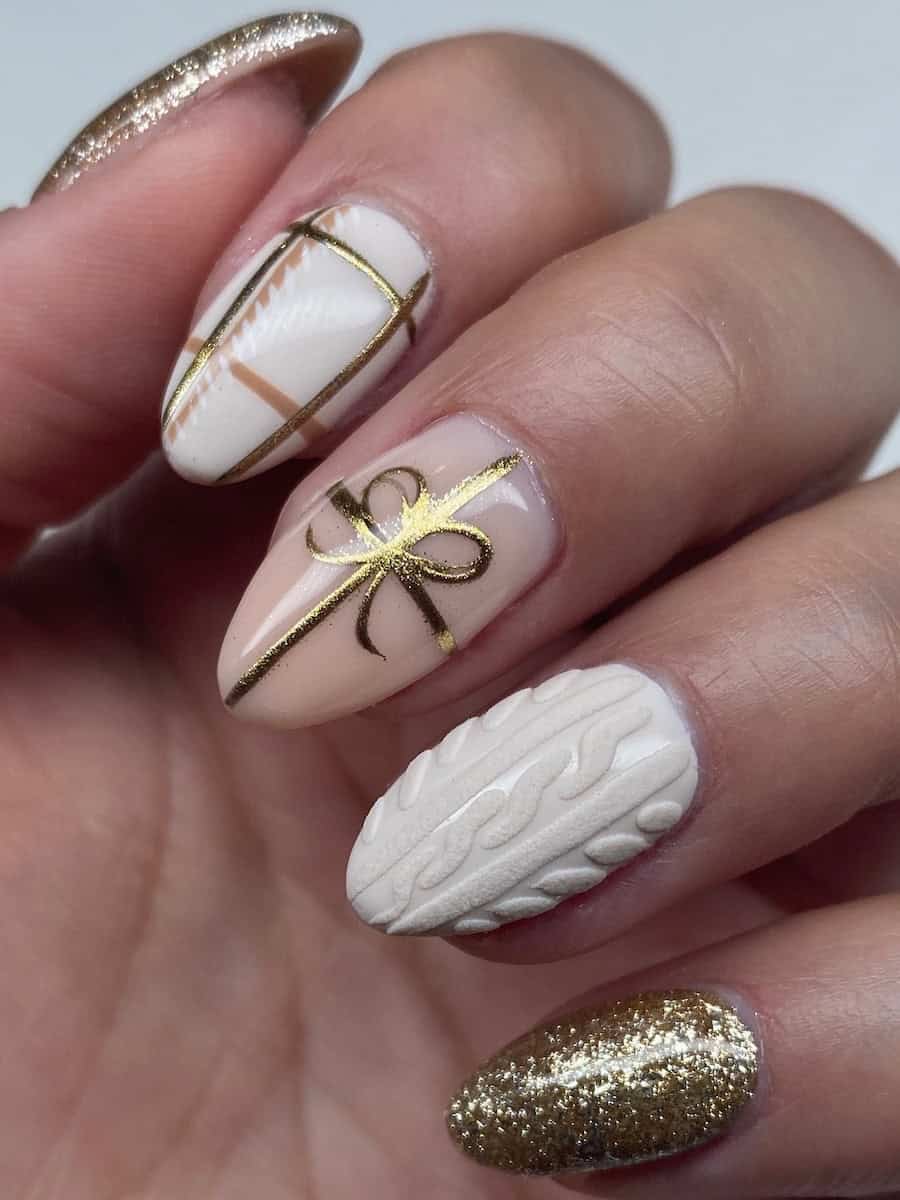 short almond nails featuring white, gold, and cream colored polish with sweater nail art, plaid, and ribbon and bow accents