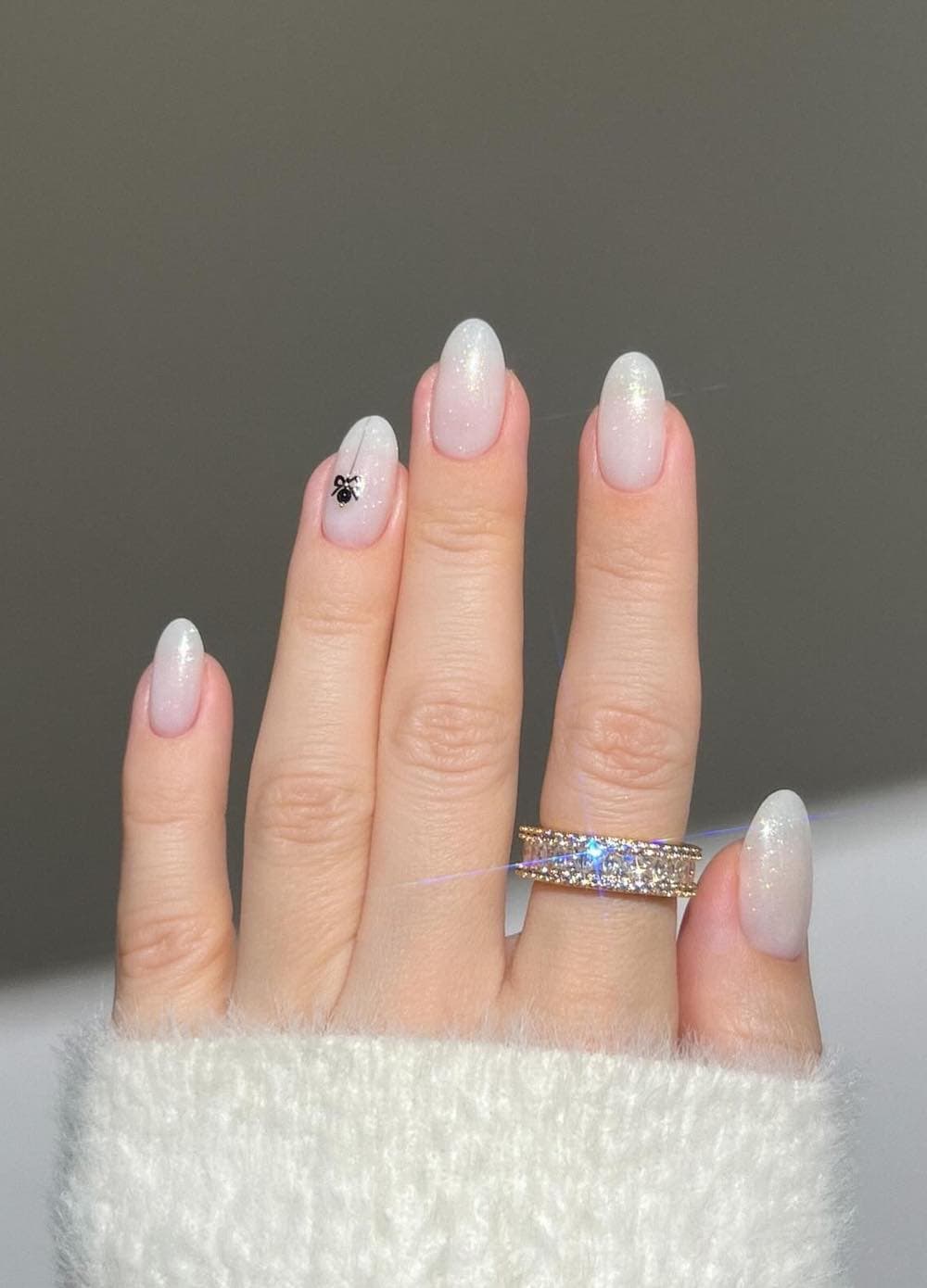 short glittery white round nails with a small ornament accent