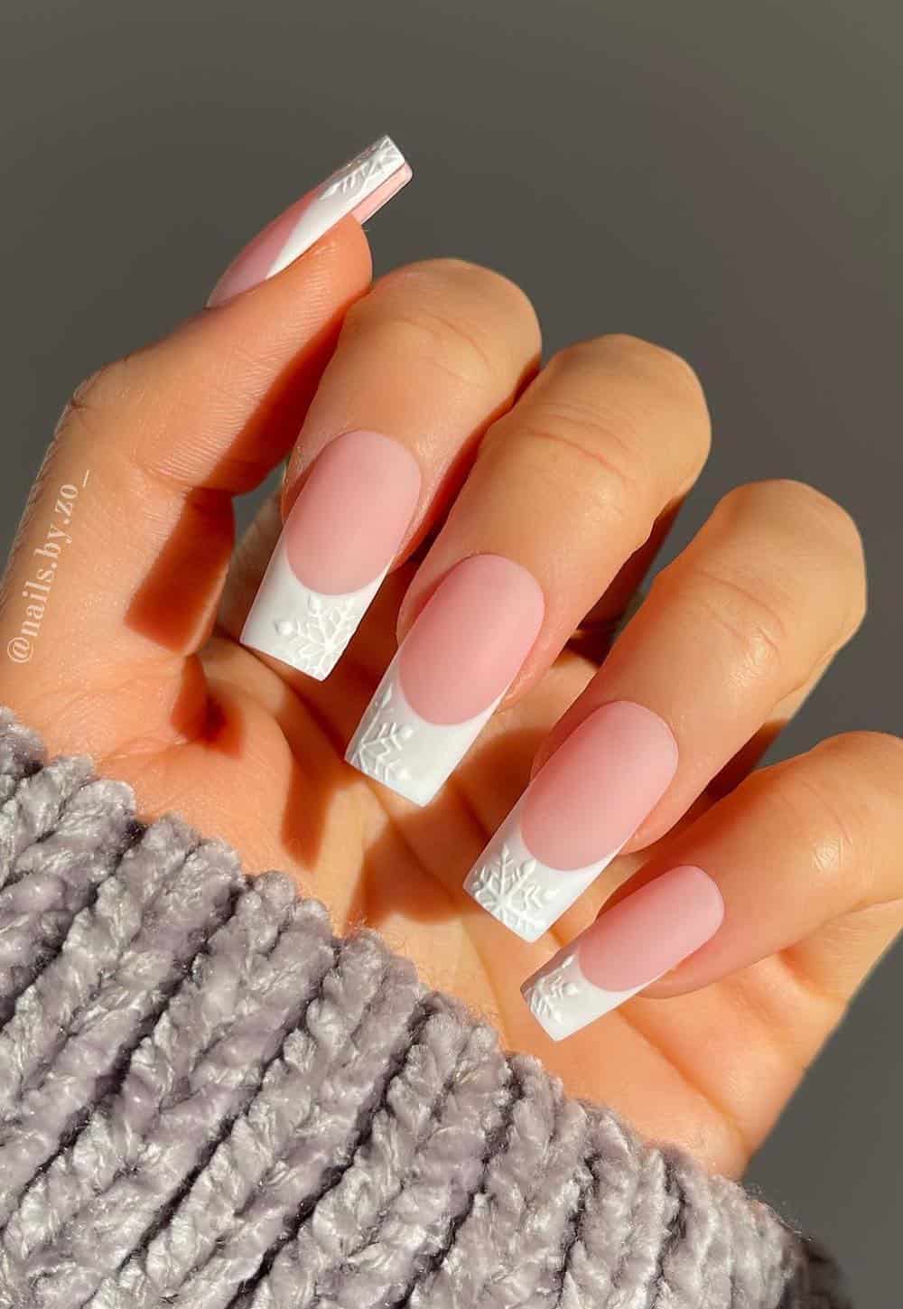 long square nude pink nails with white tips and snowflake details