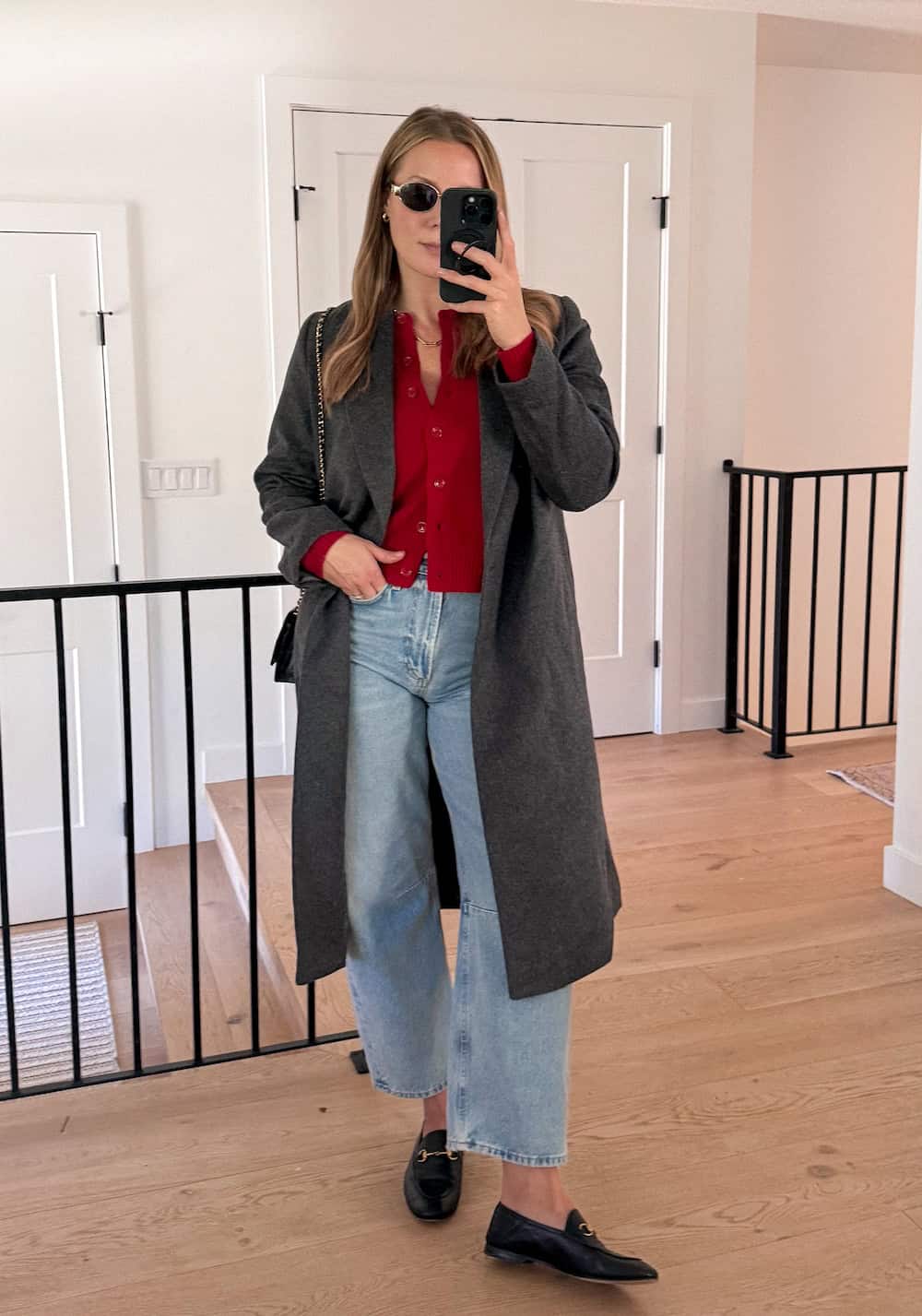 Christal wearing wide-leg jeans with a red cardigan and a long coat and loafers.