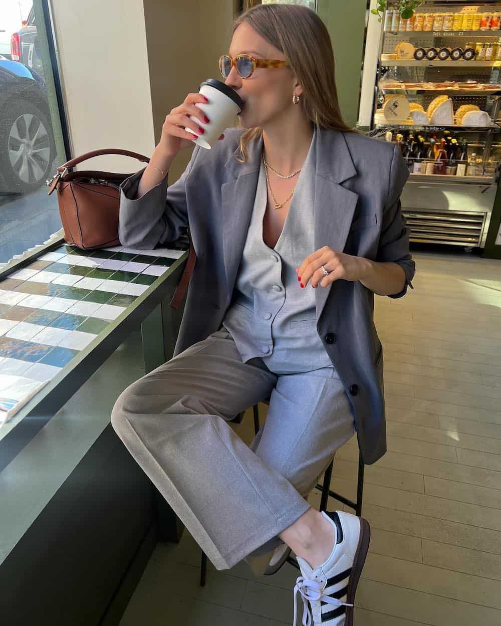Woman wearing a matching pant and vest outfit with a blazer.
