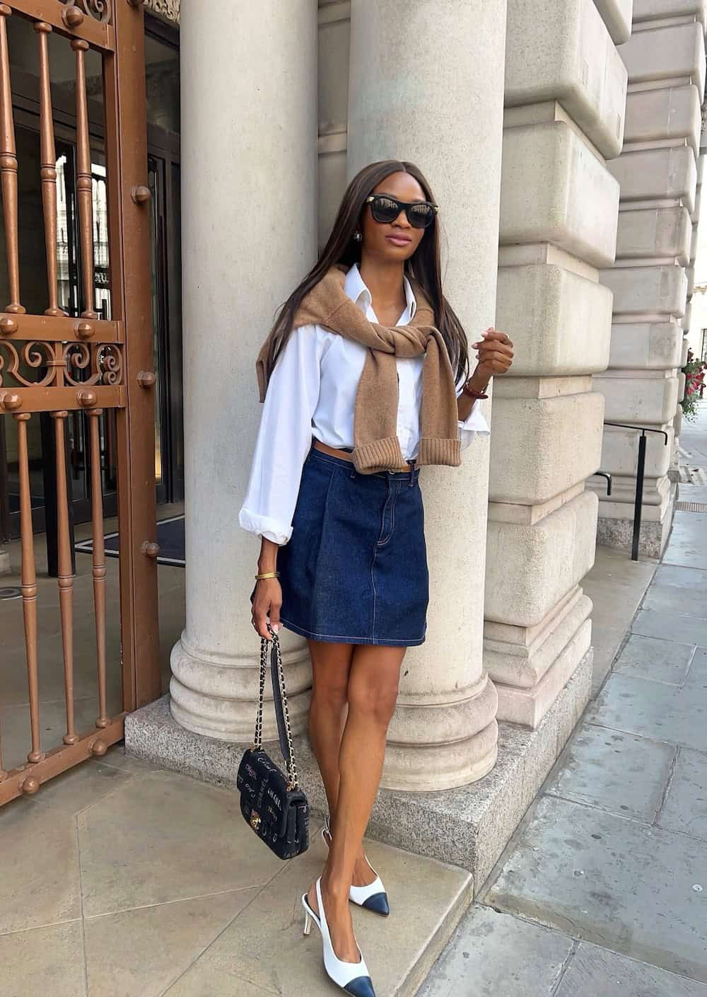 Woman wearing a denim skirt with a white button down and white sling back heels