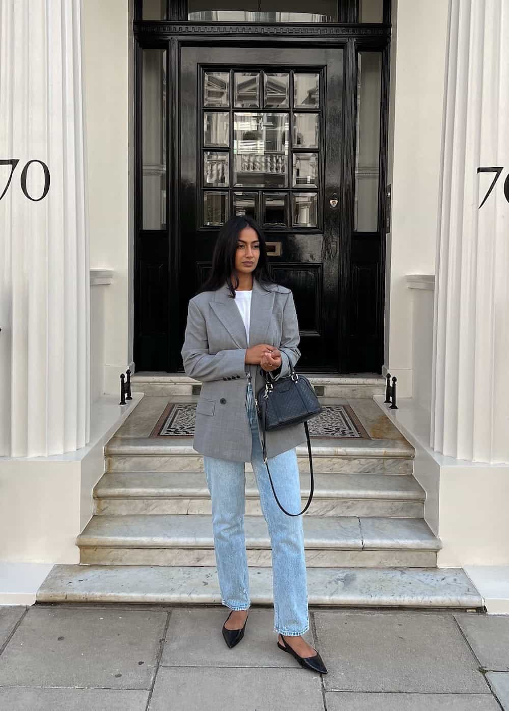 Woman wearing jeans, a white tee and a blazer with flats.
