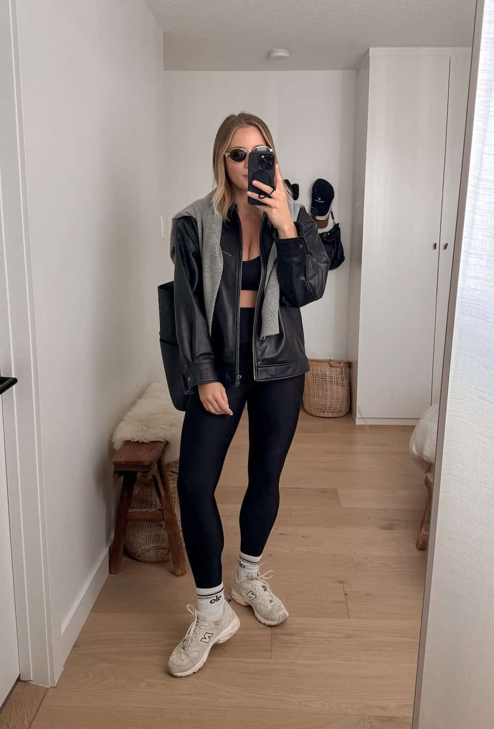 Christal wearing leggings, a sports bra and a leather jacket with New Balance sneakers.