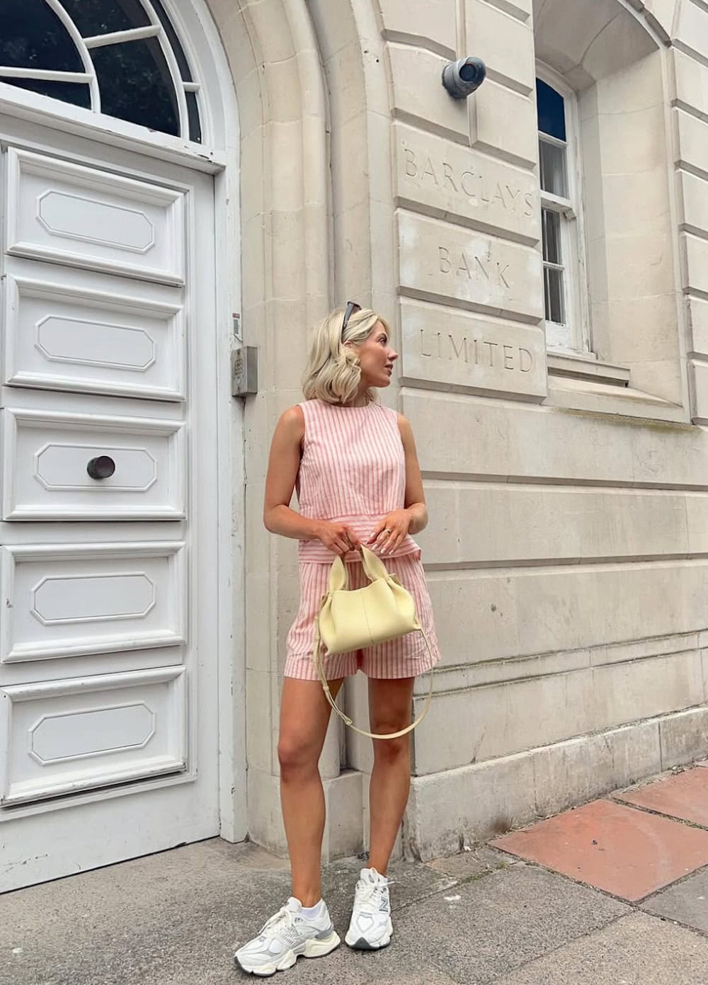 Woman wearing a linen short and tank set with New Balance sneakers.