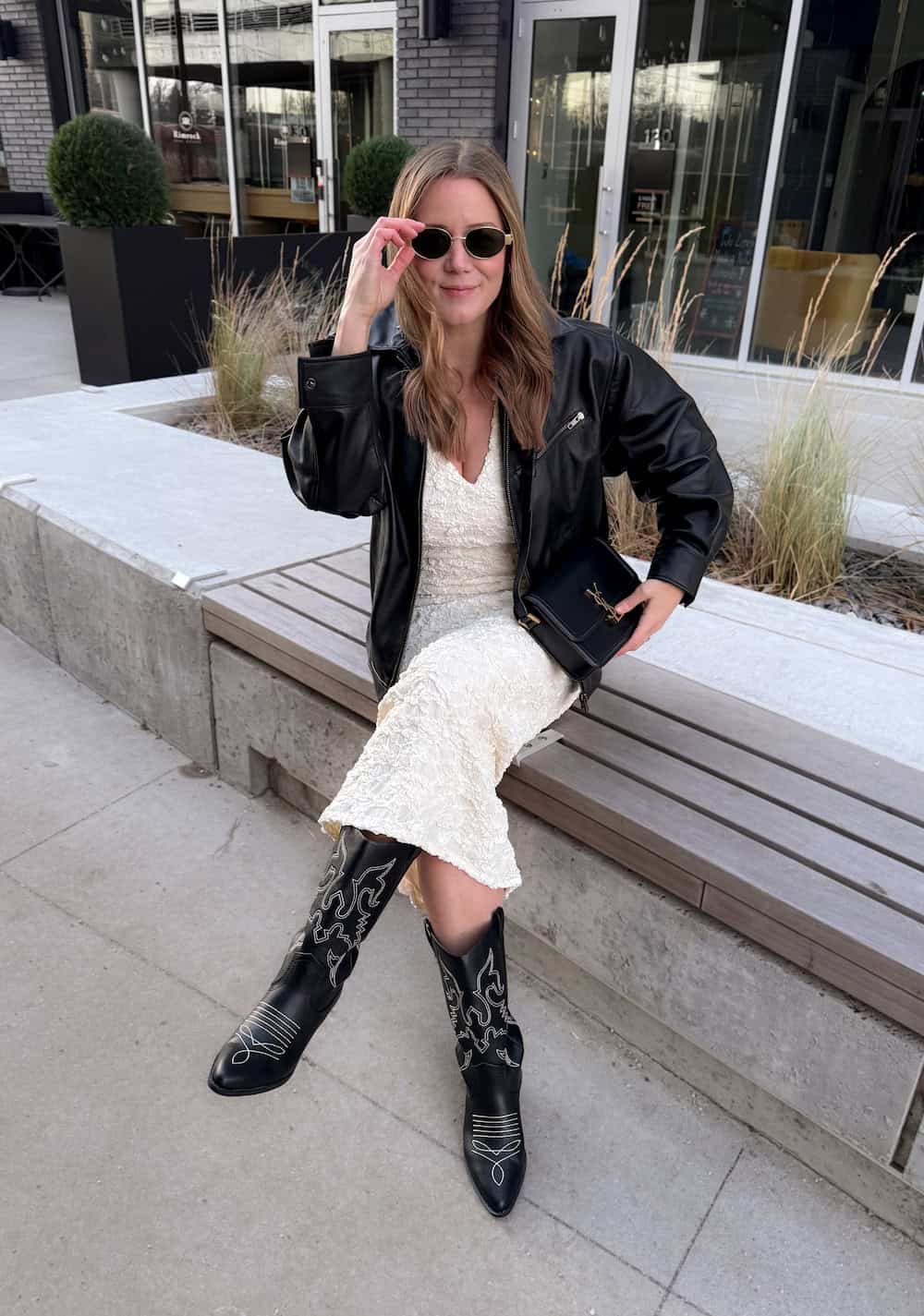 Christal wearing a white dress with black boots and a black leather jacket.
