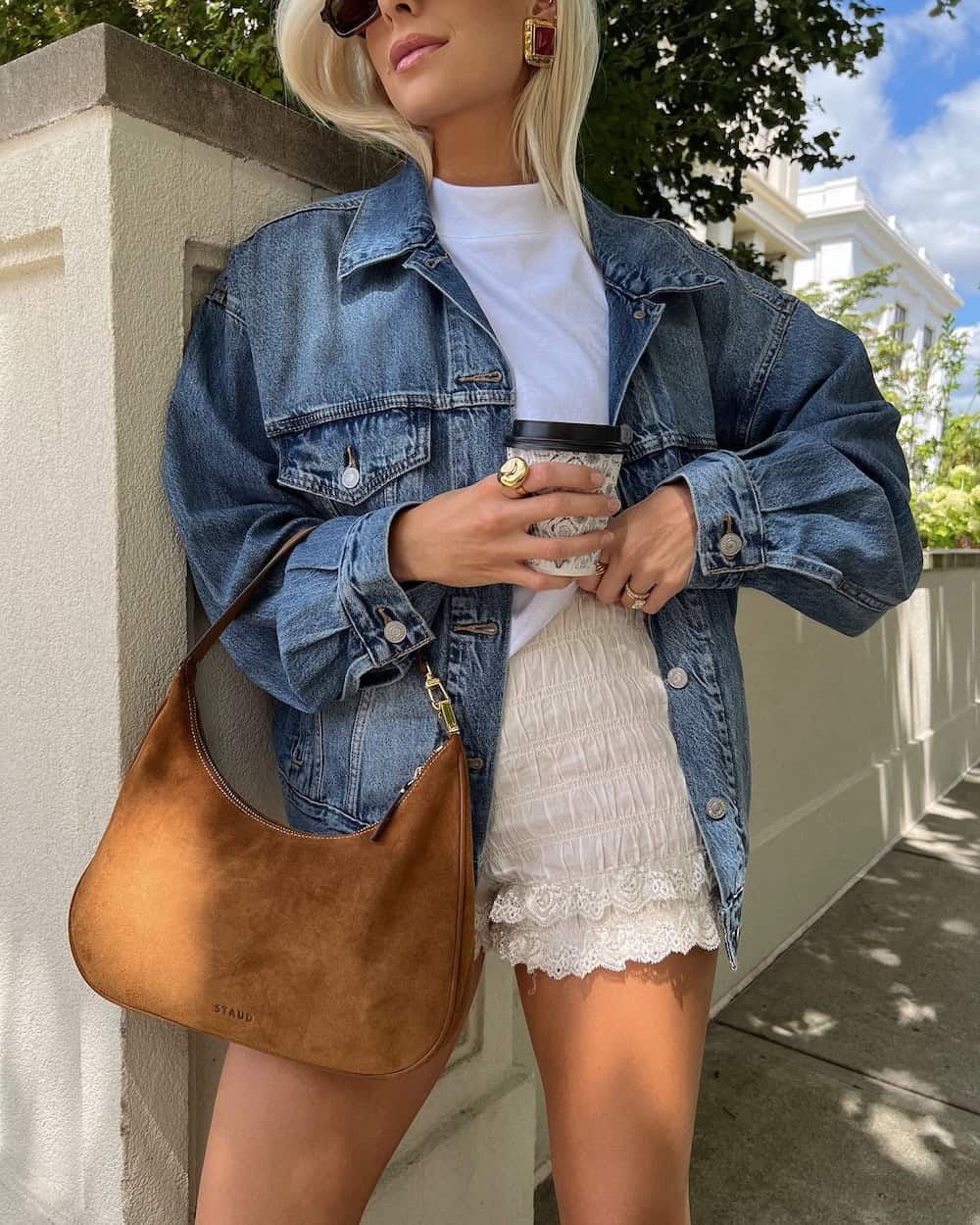 Woman wearing bloomer shorts with a white t-shirt and a denim jacket.