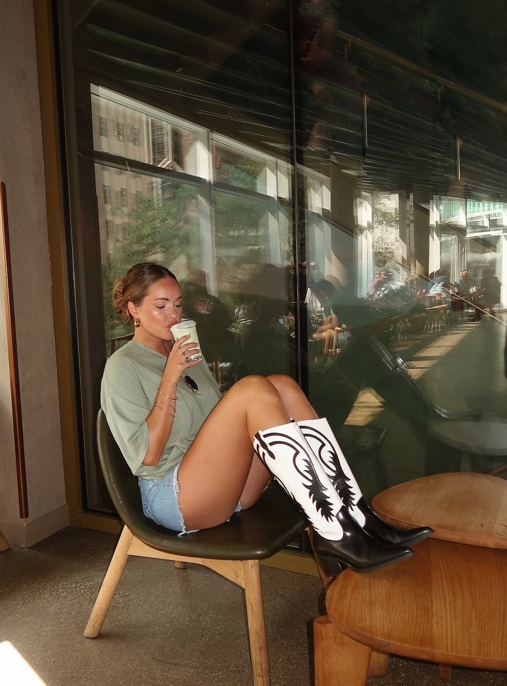 Woman wearing denim shorts with a t-shirt and boots.