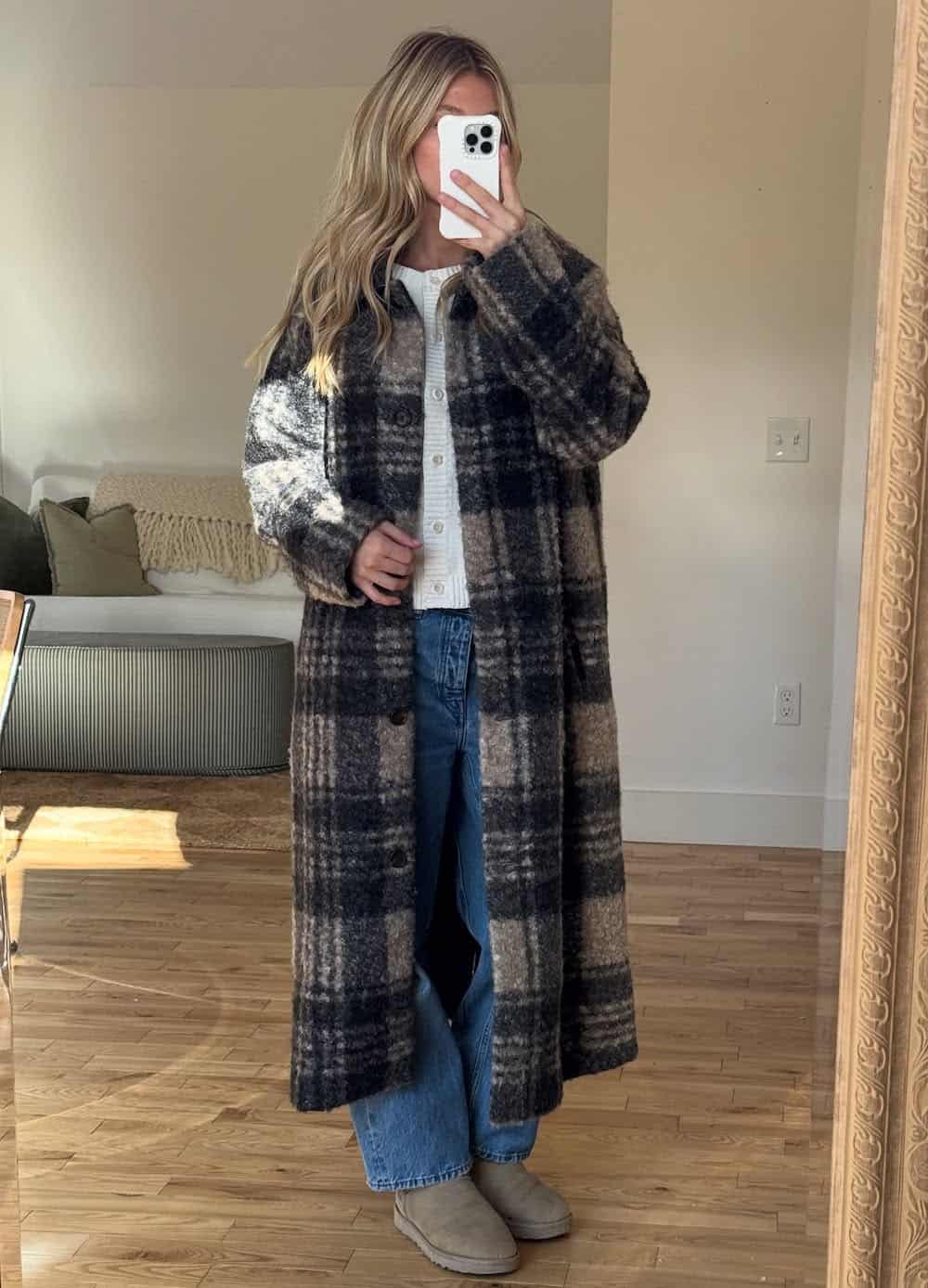 a woman wearing blue jeans, uggs, a white cardigan, and a long patterned jacket